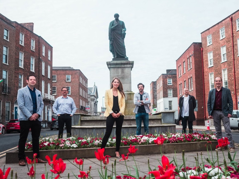 Group of people standing beside a statue in Limerick.