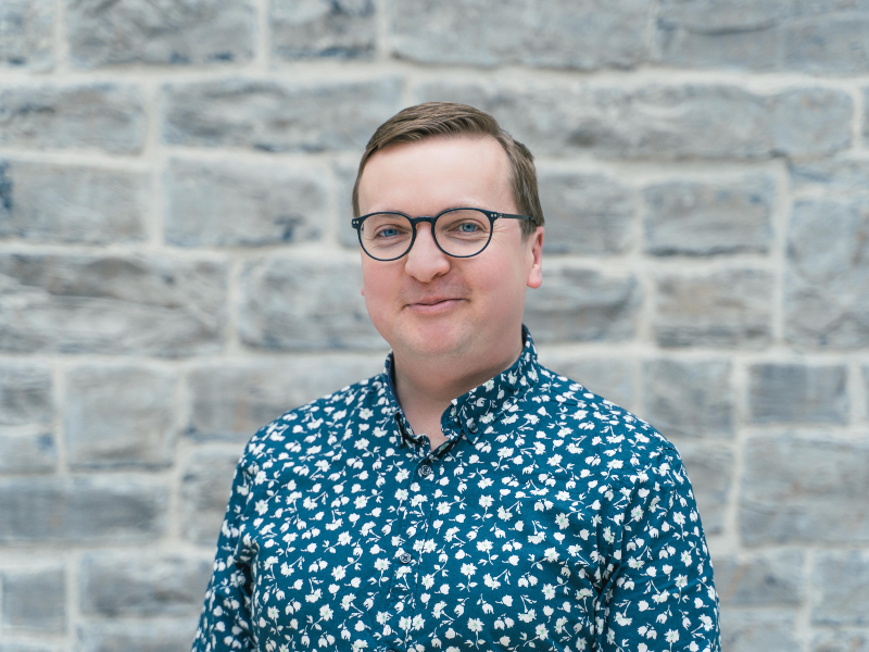 Man in glasses wearing green patterned shirt.