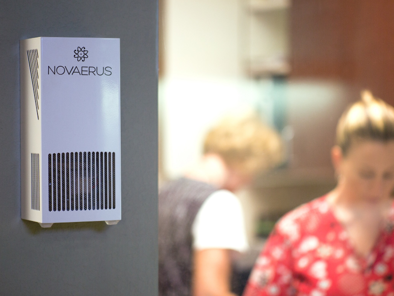 Wall-mounted air-cleaning device on a wall in a workplace.