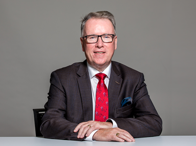 Well-dressed man in grey suit and glasses.