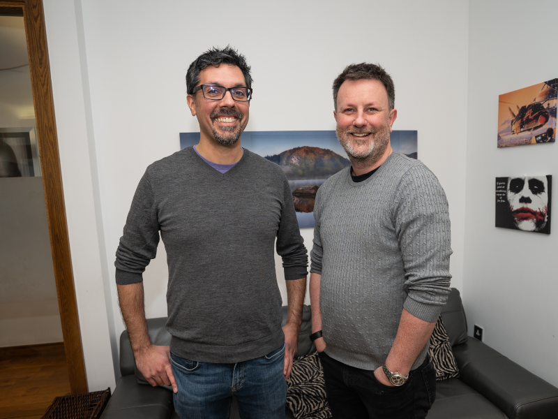 Two men with beards wearing jumpers smiling.