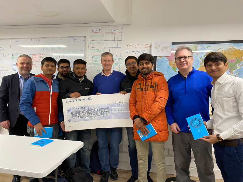 Group of men holding a big cheque.