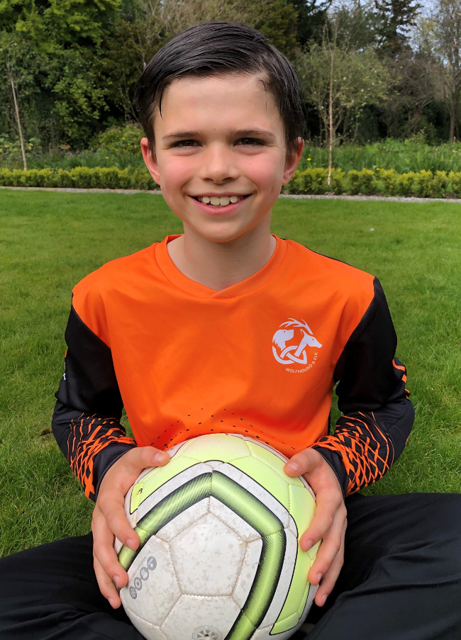 Young boy wearing orange and black football jersey.