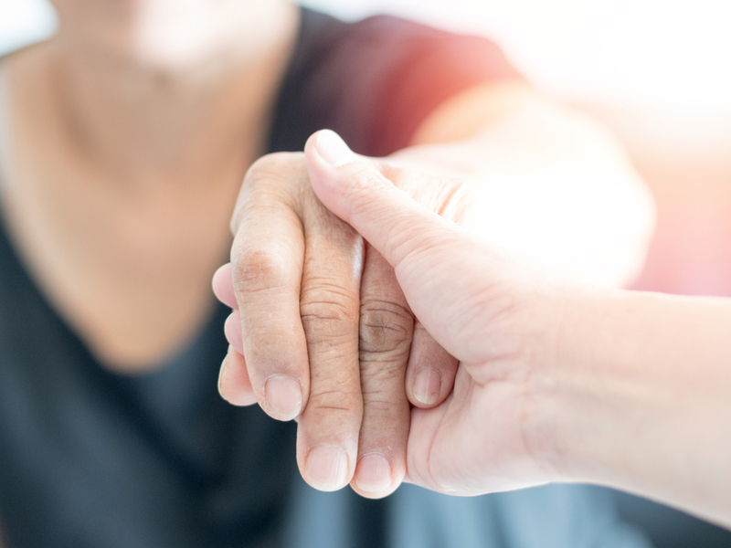 Young woman holding elderly relative's hand.