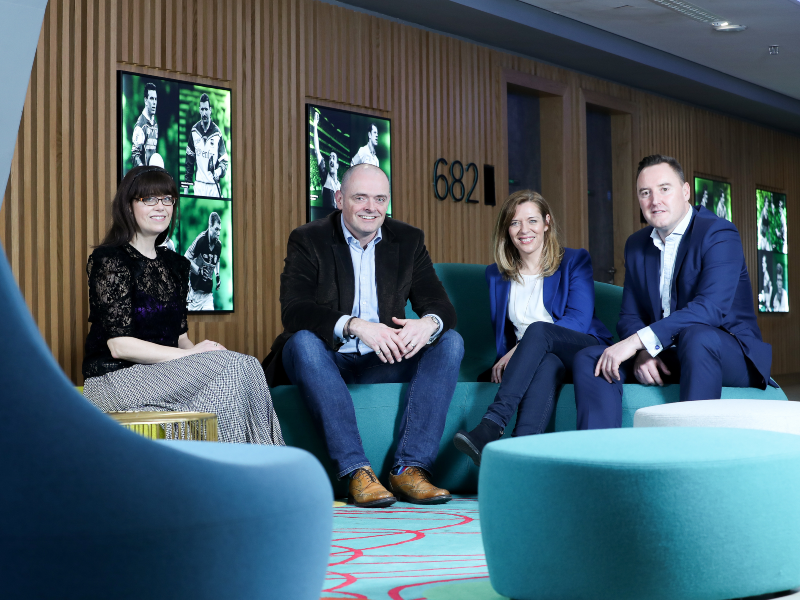 Two men and two women sitting on blue-coloured couches.