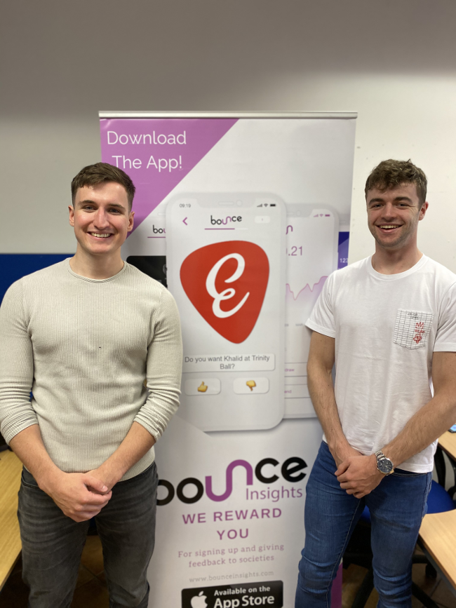 Two young men beside a sign that says Bounce.