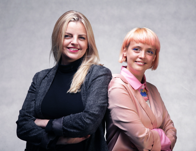 Woman with blond hair and a woman with pink hair.