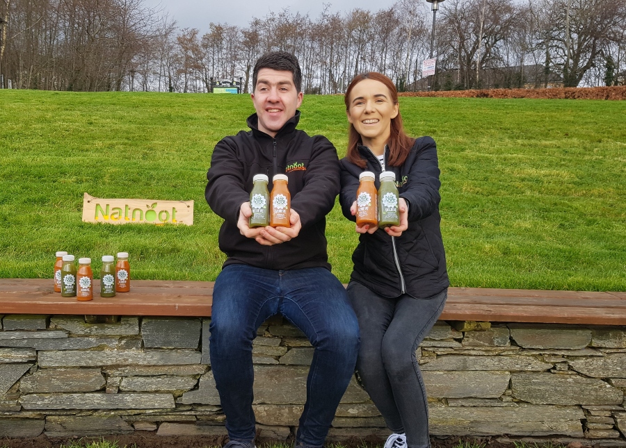 Man and woman sitting on a wall holding drinks.