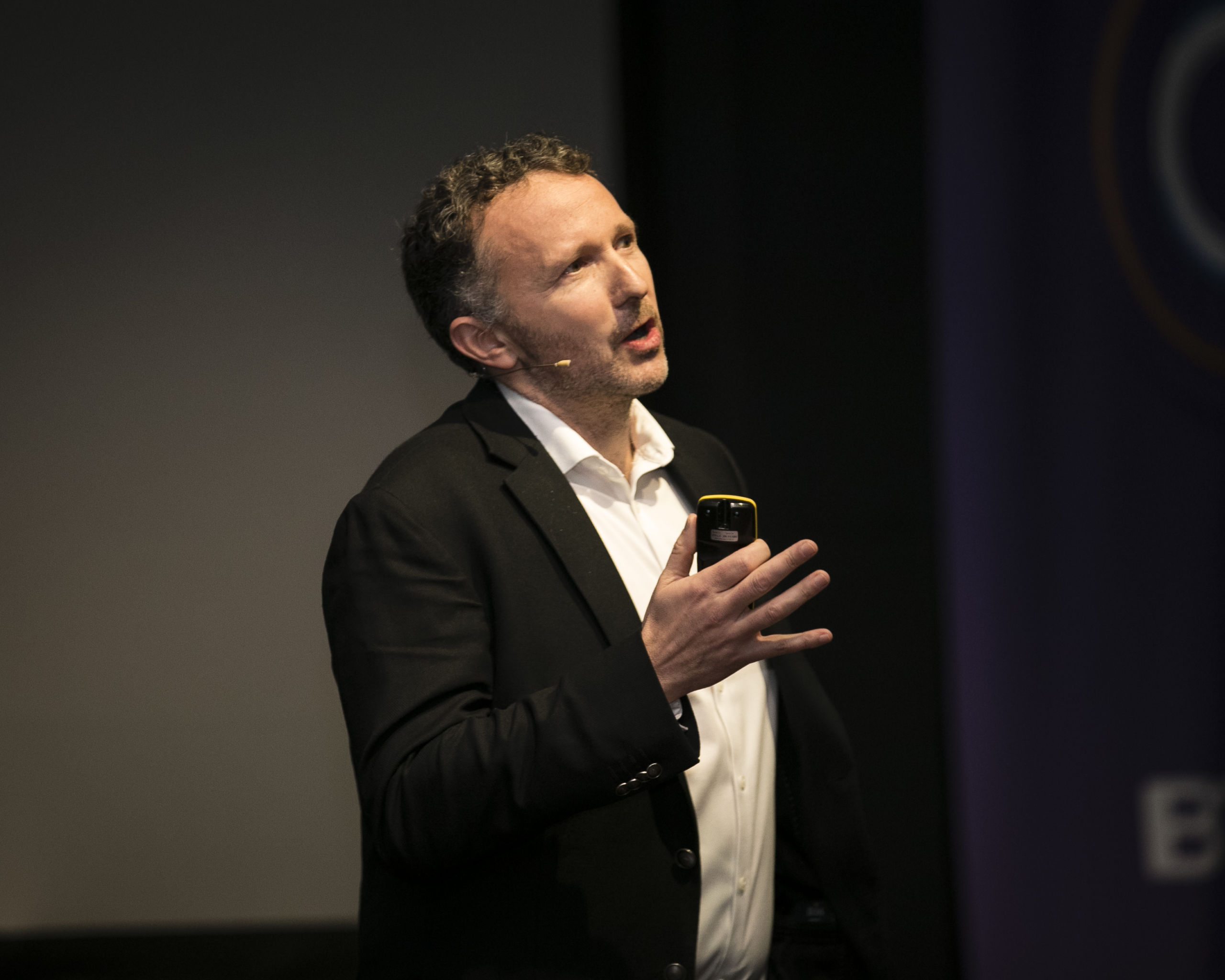 Man in black jacket talking on stage.