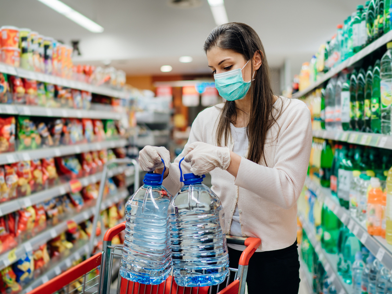 woman in supermarket shopping while wearing a mask.