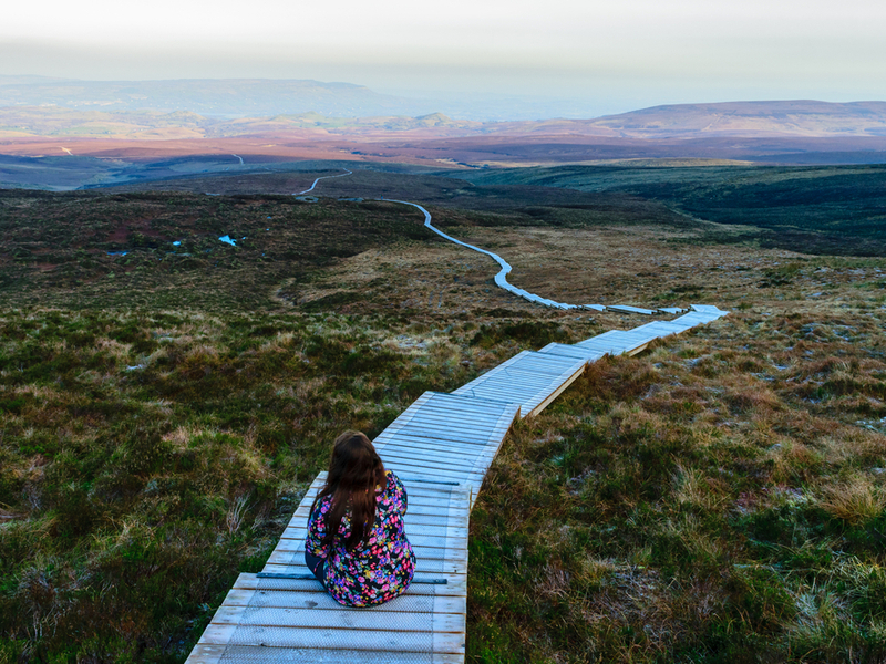 Young girl sits on stairway walking path in mountains in Fermanagh.