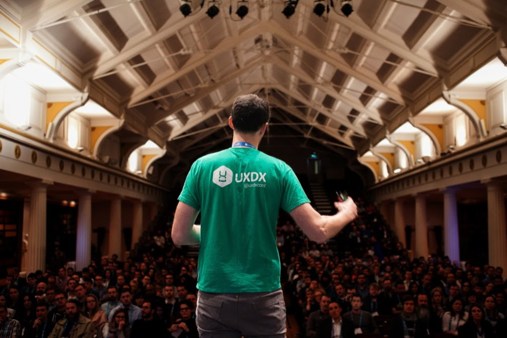 Man in green t-shirt addressing a crowd.