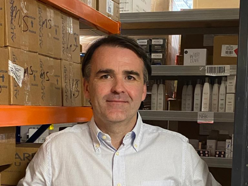 Dark-haired man in white shirt in a warehouse.