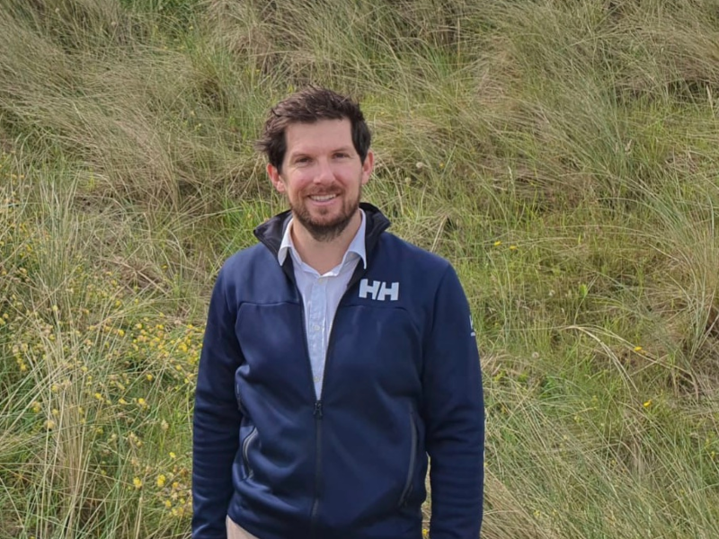 Man in blue jacket standing in a field.