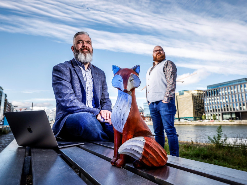 Two men standing on a dublin dock behind a fox.