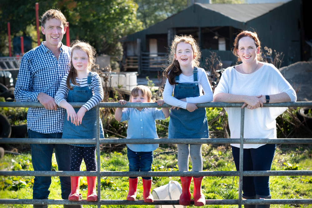 family leaning against a gate on an Irish farm.