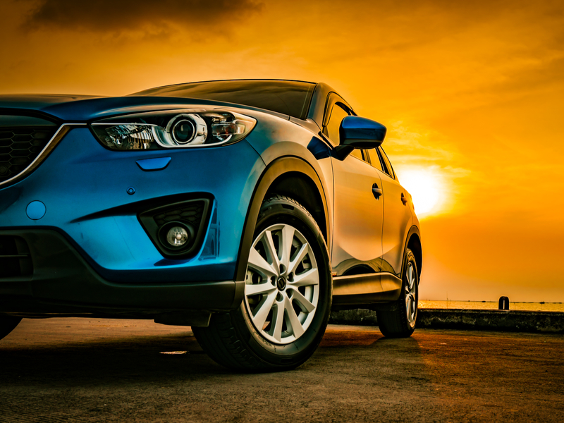 blue SUV under a yellow evening sun.