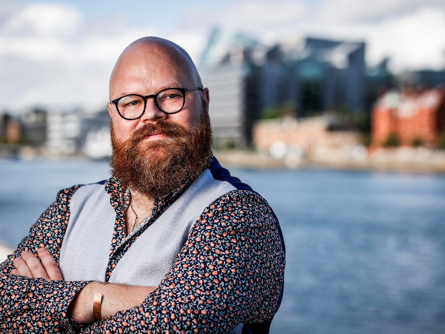 Bearded man with arms folded.