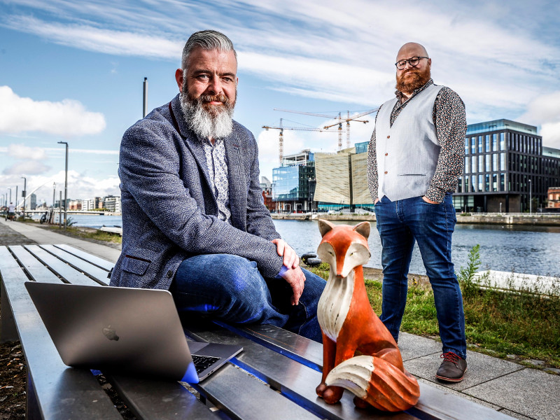 Two men standing at docks in Dublin behind a fox.