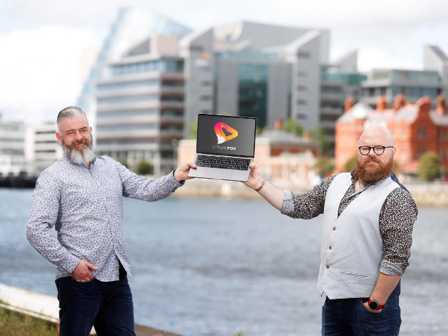 Two men holding a computer on Dublin docks.