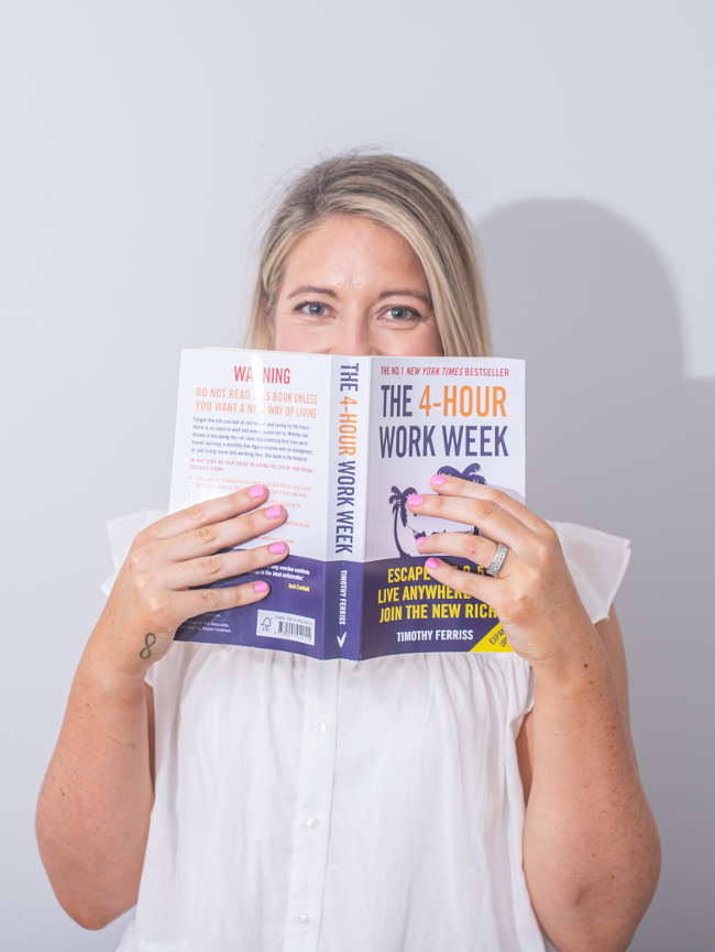 blonde woman holding book to face.