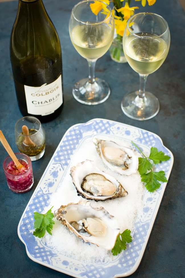 oysters on a plate beside glasses of white wine.