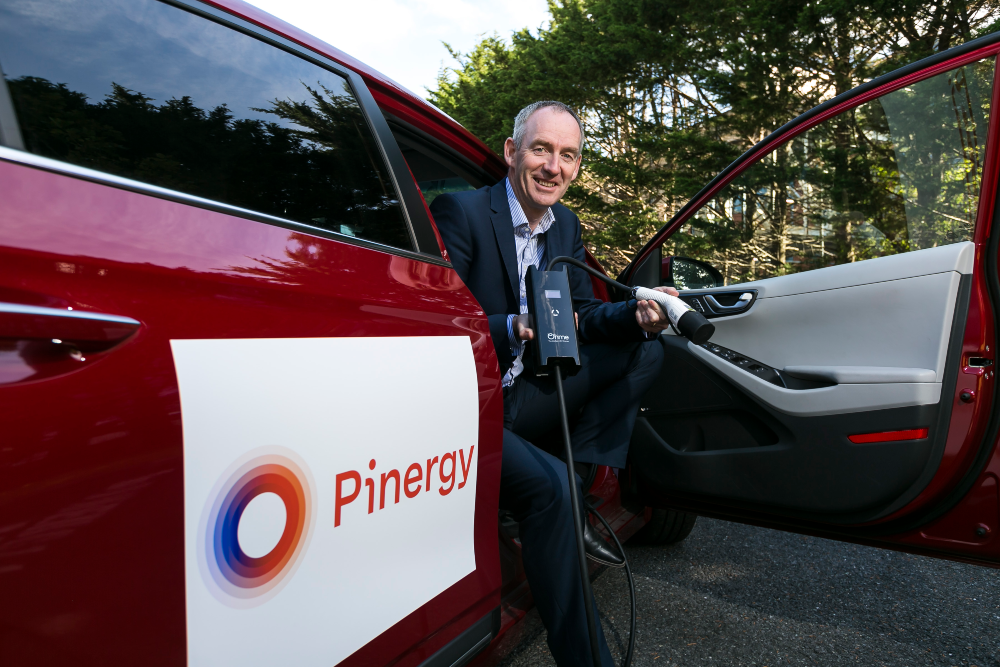 Man sitting in electric vehicle with charger.