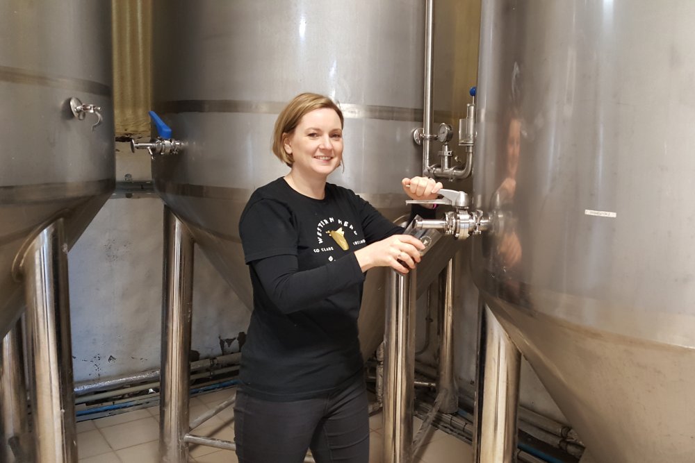 Woman pouring beer from a giant vat.