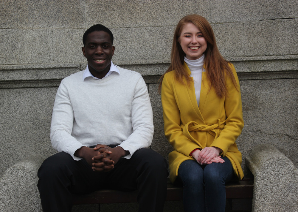 man in white jumper beside woman in yellow coat.