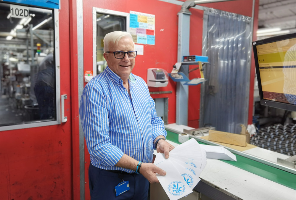 Man in blue shirt holding envelopes.