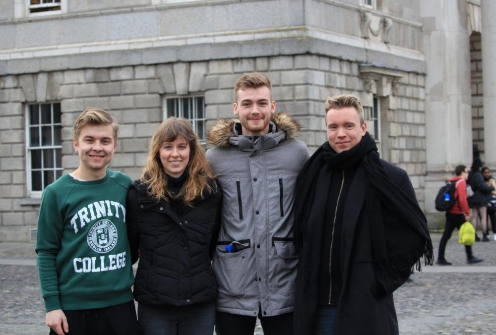 Three men and a woman standing at Trinity College Dublin.