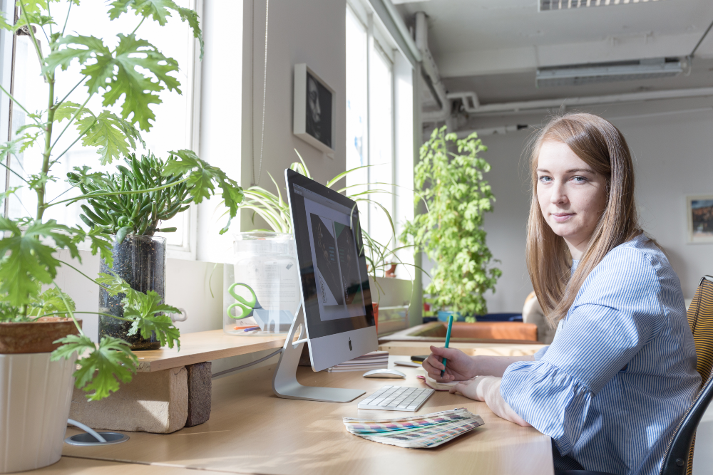 Young woman in blue blouse designing at a computer.