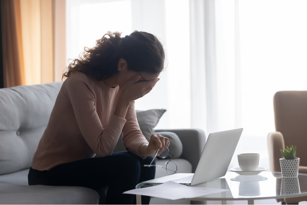 Stressed out young woman working from home with head in hands.