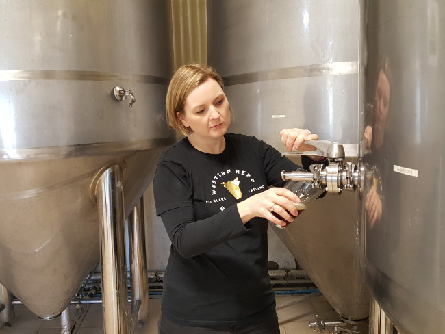 Woman pouring beer from giant vat.