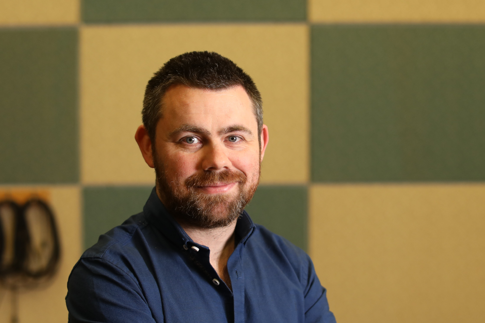 dark-haired bearded man in a broadcast studio.