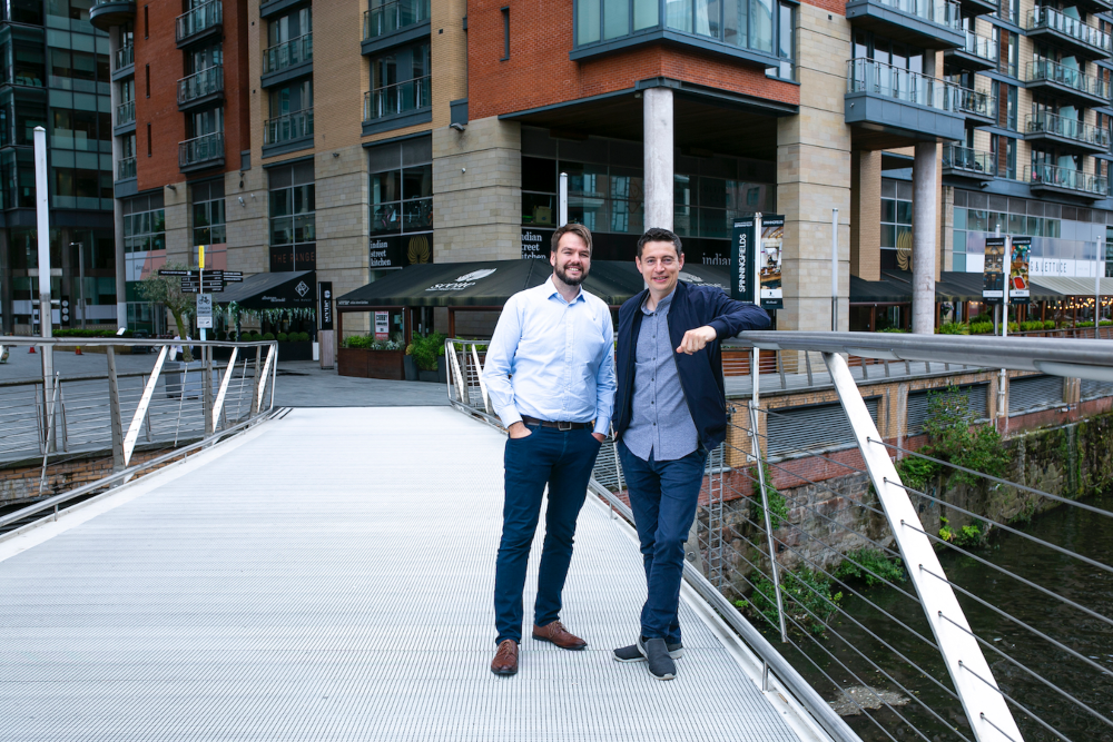 Two men standing on a bridge.