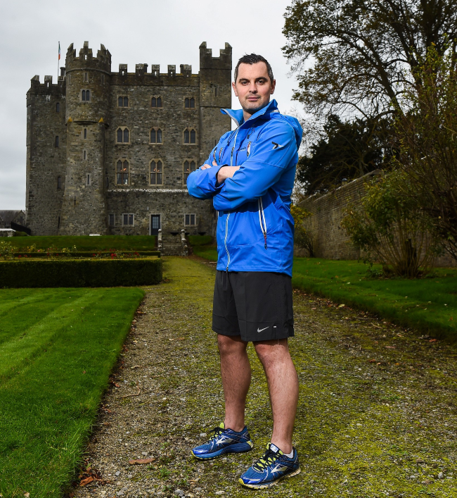 Man in blue top standing in front of a castle.