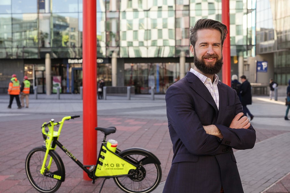 Man standing with yellow bike in Dublin's Silicon Docks.