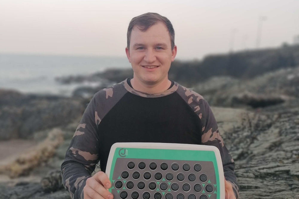 Young entrepreneur holding up a musical instrument he invented.