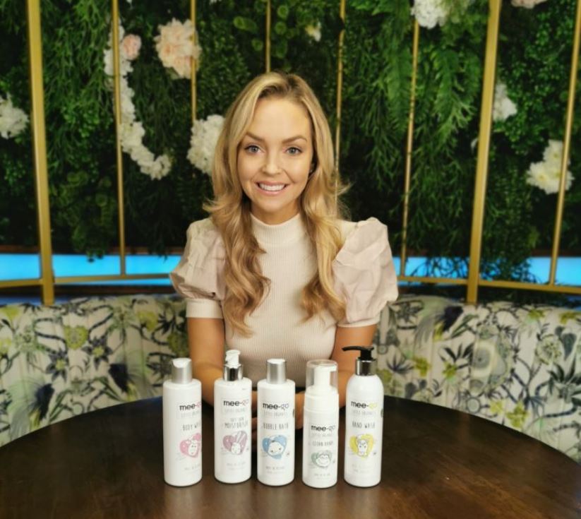 Woman with blonde hair behind a range of products.