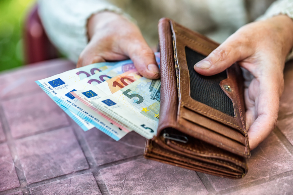 Elderly woman putting cash into her purse.