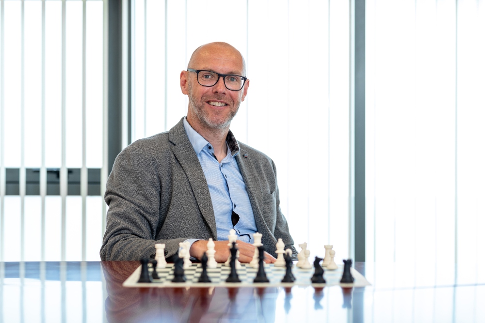 Man sitting at a table with a chess set in front of him.