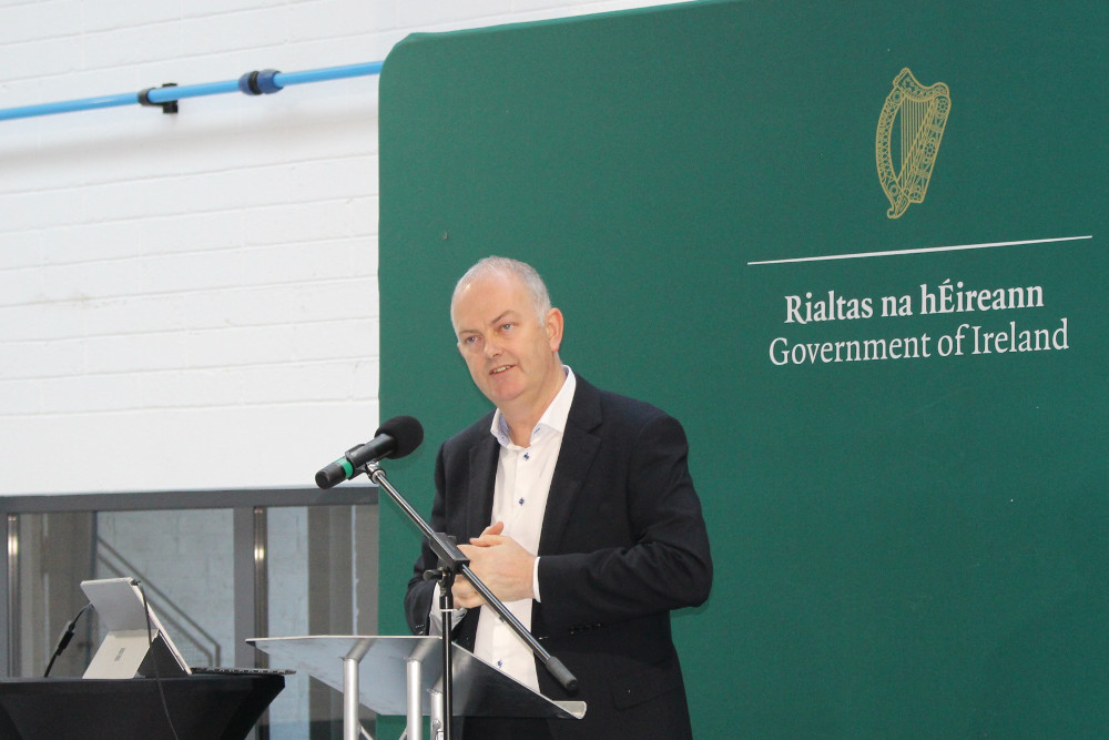 Man in black jacket speaking on a podium.