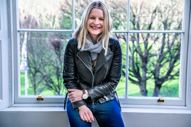 Smiling blonde woman sitting at window.