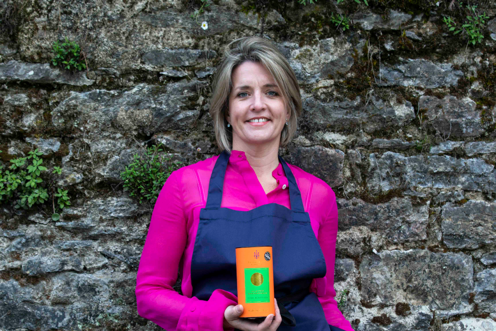 Woman in pink blouse, blue apron holding a box of biscuits.