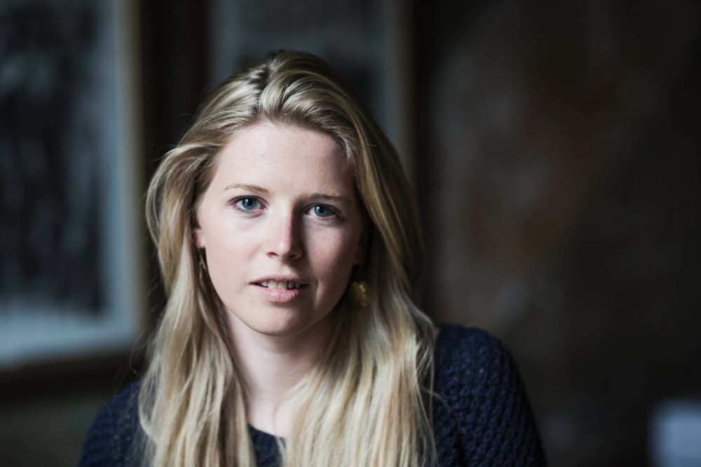 Young blond-haired woman in navy top.