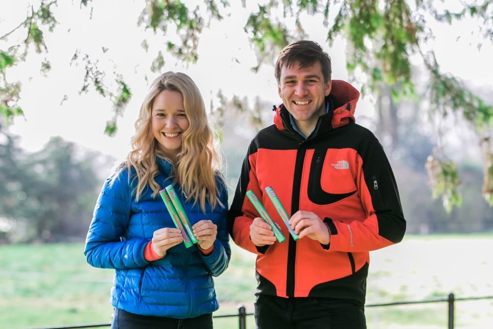 Man and woman holding biodegradable toothbrushes.