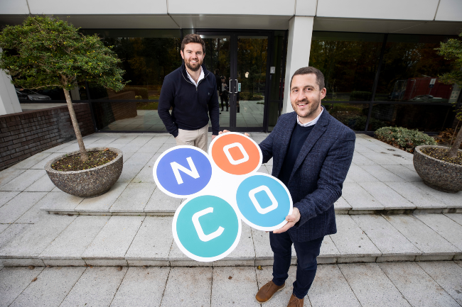 Two men holding a sign saying NoCo.