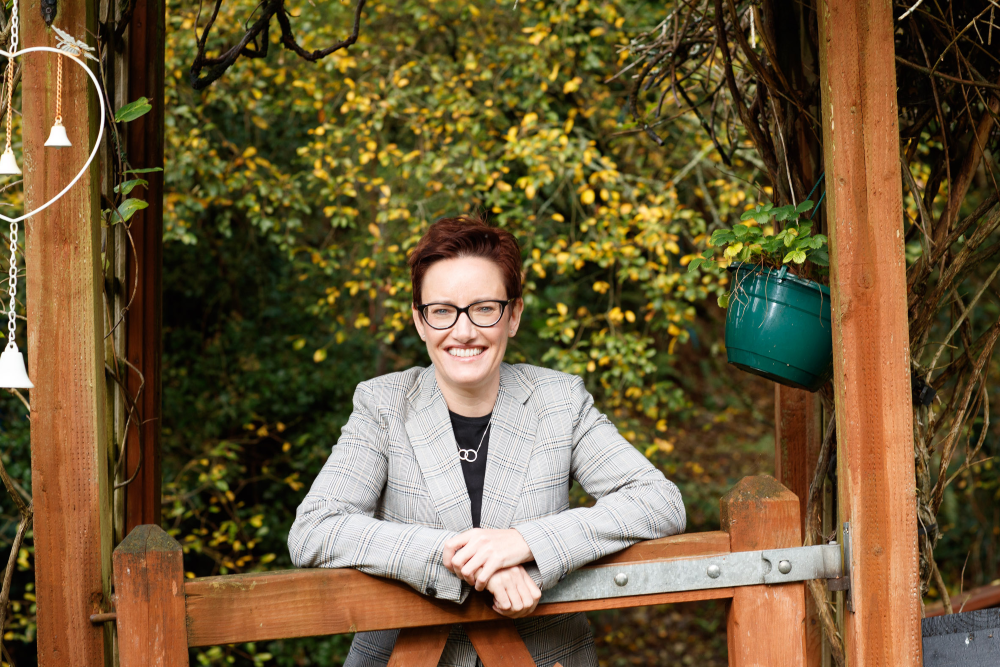 Smartly dressed woman standing at a gate.