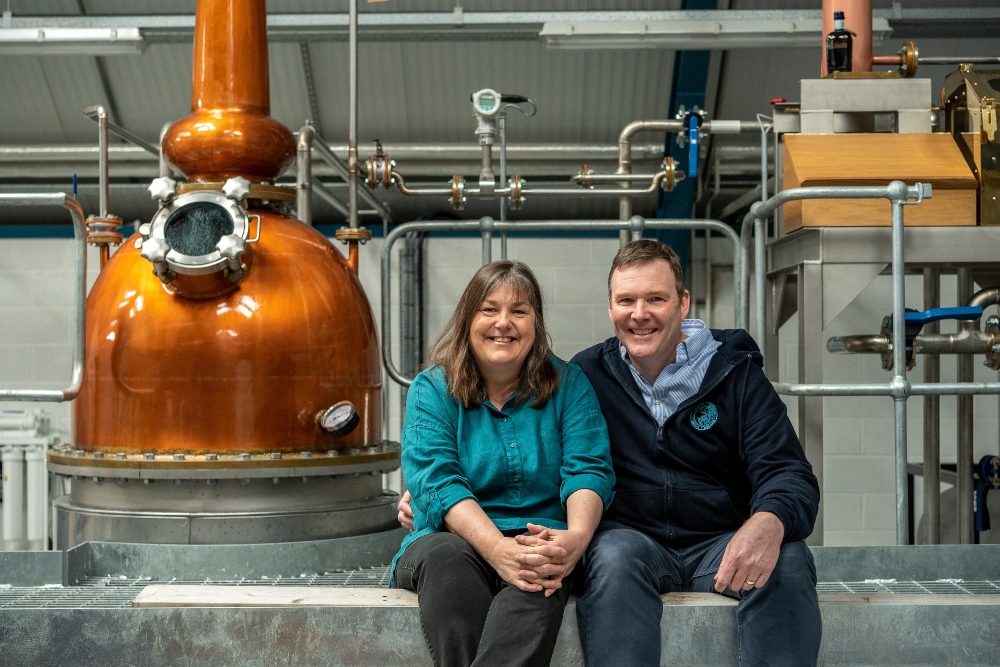 Man and woman sitting in front of a whiskey still system.